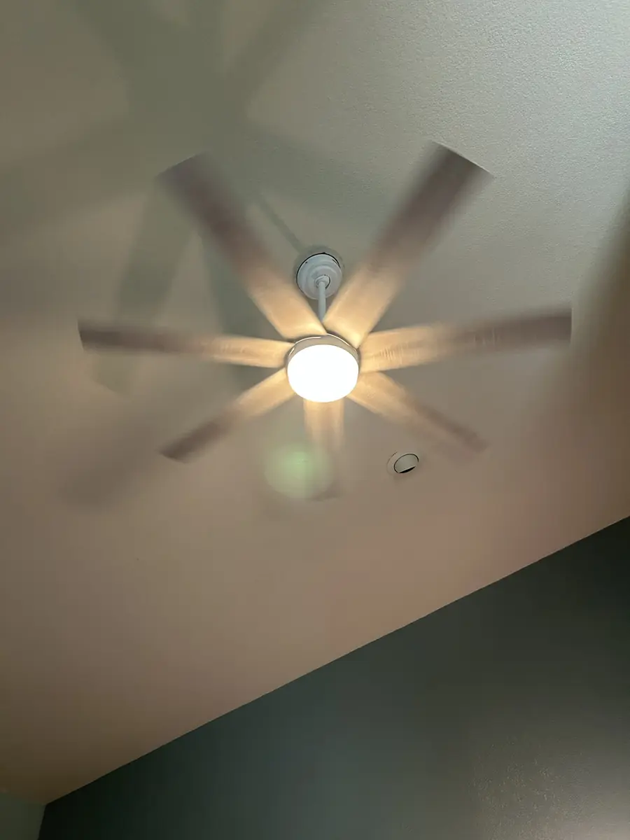 Ceiling fan with a glowing light kit spinning on a sloped ceiling