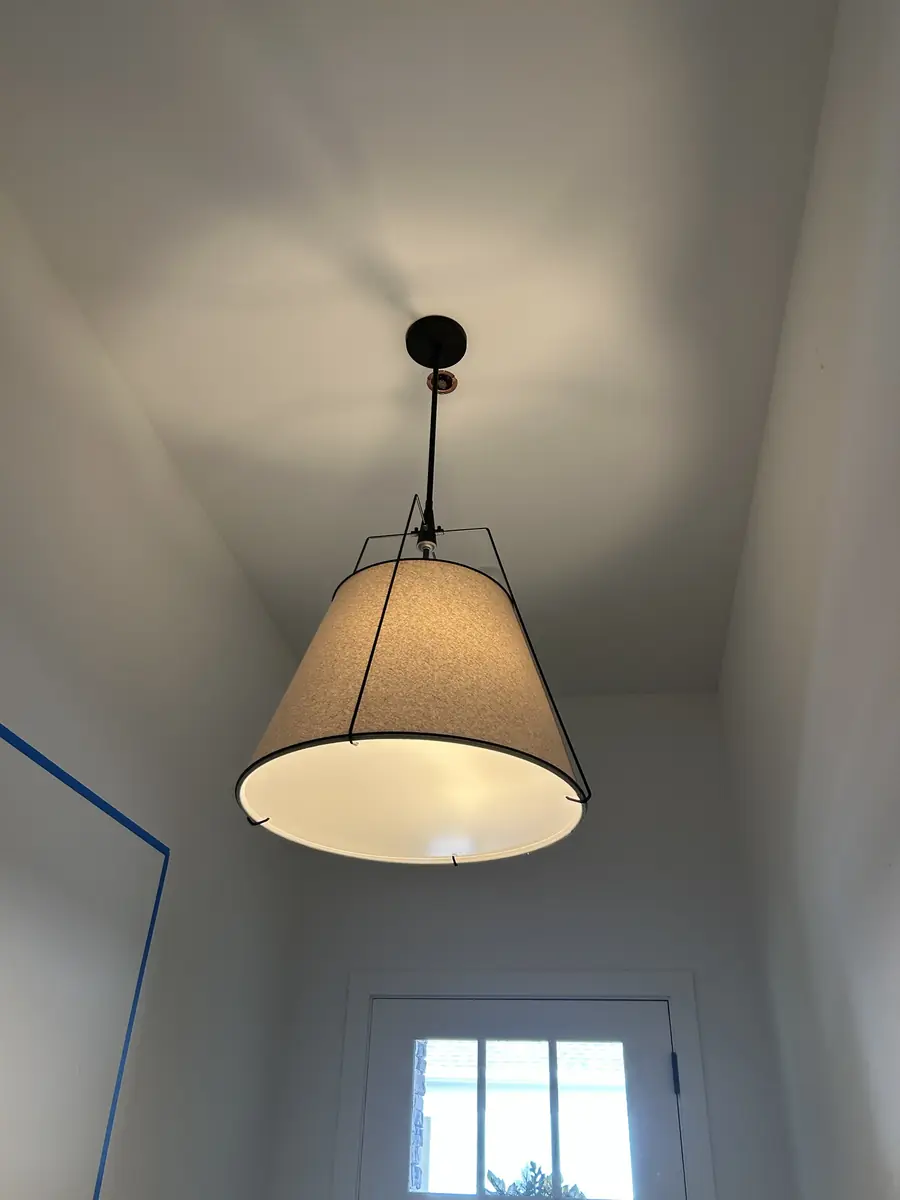 Large drum-shade pendant light hanging in a bright entryway